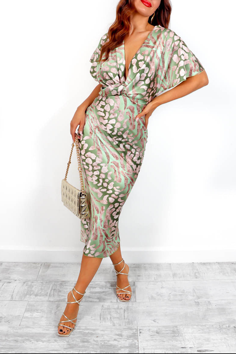 Woman wearing a green and white patterned dress with a white background