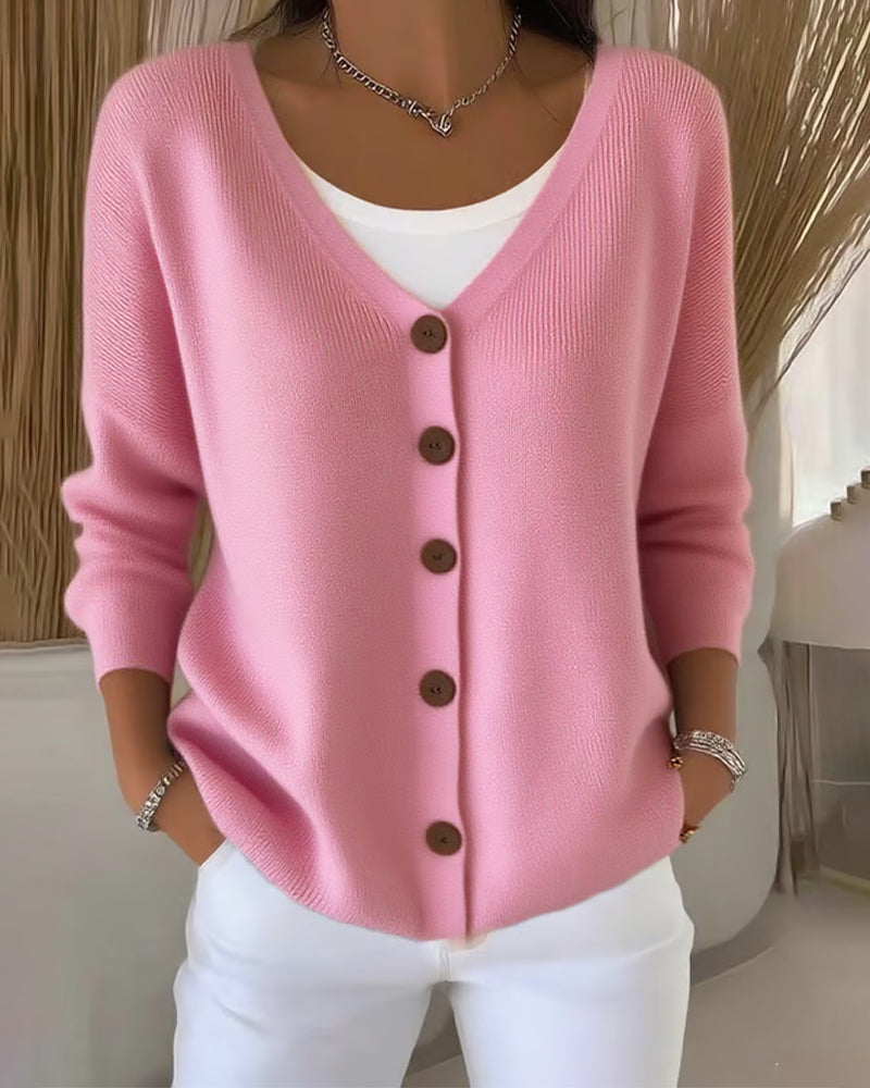 Pink cardigan with brown buttons worn by a person indoors.